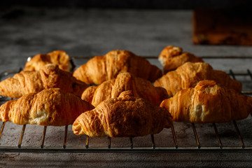 Freshly baked French croissants with cappuccino milk on a dark background with copy space.