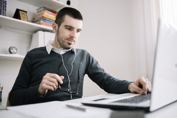 Employee listening music while working on laptop