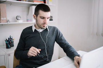 Fototapeta premium Man listening to music while working on laptop