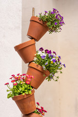 Fototapeta na wymiar planted colorful flowerpots stacked as decoration in front of a white wall