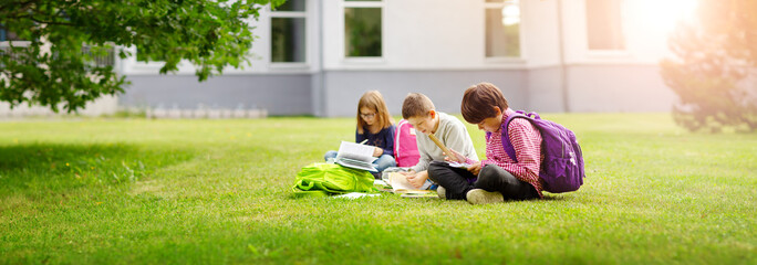 Children with rucksacks standing in the park near school