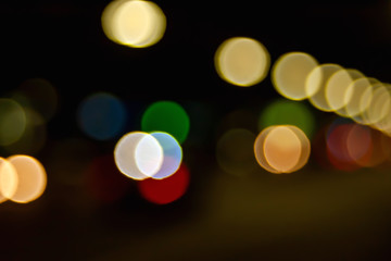 Bokeh of the road. Blurred image of light of street lamps and headlights of cars at night in the city.