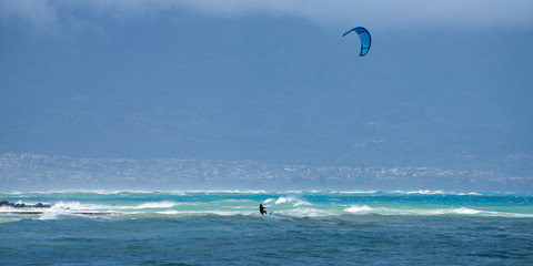 Panoramic view of the ocean with kite surfer on a windy day on Maui island in Hawaii.