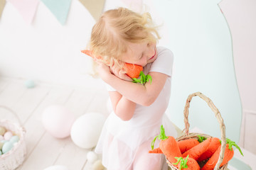 Fototapeta premium Blond girl playing and smile in kid room with easter decoration carrot toy 