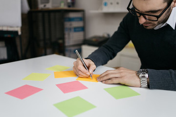 Office worker with eyeglasses writing notes using pen