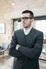 Broker in tuxedo standing with crossed hands