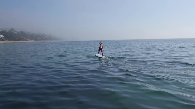 Person paddleboards in California, wide aerial