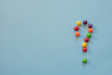 colored round sweets on a blue background. Question mark