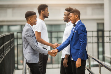 team of young african men near the building shake hands