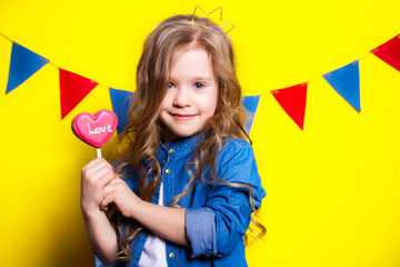 Princess girl with candy heart in hands on a yellow background with a garland of flags. Thematic children's birthday.