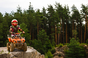 Girl riding quad bike mountain, ATV. Cute child on quadricycle. Kids summer vacation activity. © Angelov