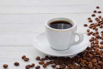 Cup of coffee on plate on white wooden table
