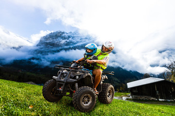 Happy family riding and looking quad bike on mountain. Cute boy on quadricycle. Family summer vacation activity. © Angelov