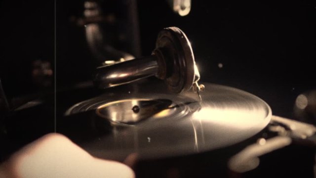 gramophone is turned on. needle is put on rotating disk. Black dark background. Video footage. Retro vintage style part. Shallow depth of field. stylized in post-processing added scratches and noise