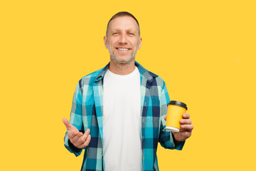 Smiling bearded man on a yellow background with coffee or tea in a yellow cup