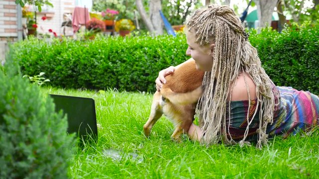 Beautiful girl lies on the grass and plays with dog. Slow motion. Sunny weather. Beautiful nature