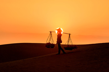 Silhouette of a hawker merchant traveling through the mui ne desert in Vietnam