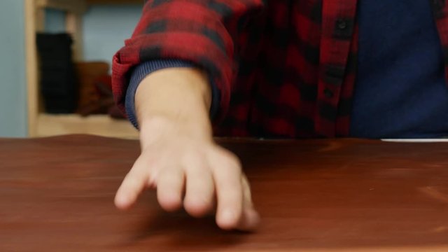 A skinner touching a big piece of leather on the table. Male leather craftsman examines skin for flaws. Determination of leather quality