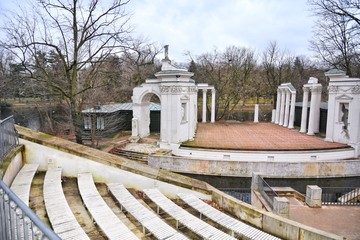 Fototapeta na wymiar Warsaw, Poland - January 2020. The Amphitheatre at the Royal Lazienki park. White ancient ruins with the function of an open air theatre. Classical theater isle stage, amphitheater in Lazenki Royal 