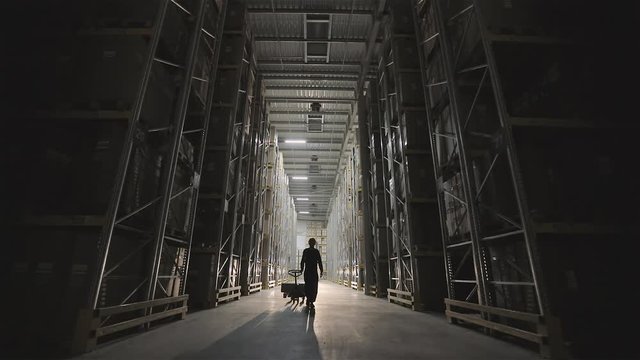 Morning in the factory, a man walks through the warehouse light turns on