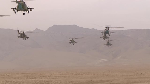 Combat link military helicopters flying over the desert between the mountains, attacking from the air of the enemy. 1
