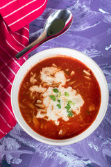 A view of a bowl of tomato soup with sour cream.