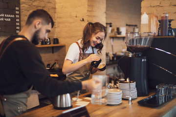 Young and cheerful barista woman make a coffee in the cafeteria