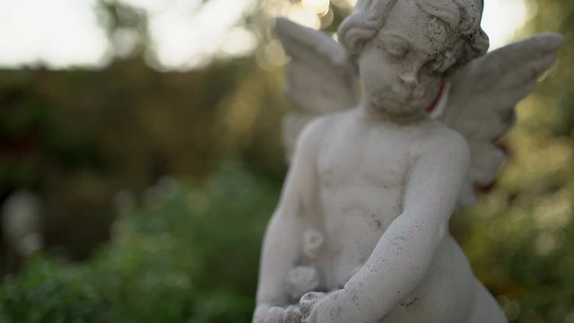Cupids statue in the garden at evening. Handheld shot