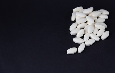 White pills on black background. Free copy space. Medical concept.