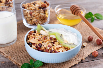 Granola with Greek yogurt kiwi and banana in a bowl with a spoon.
