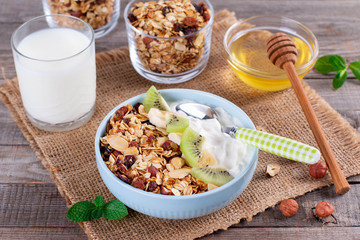 Granola with Greek yogurt kiwi and banana in a bowl with a spoon.