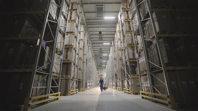 Morning in the factory, a man walks through the warehouse light turns on
