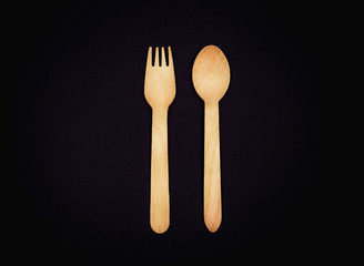 Eco wooden fork and spoon on a black background close-up