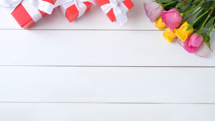 Red gift boxes and rose flowers on a gray concrete background