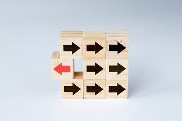 Wooden blocks with several black arrows and one block with red arrow facing the opposite direction....