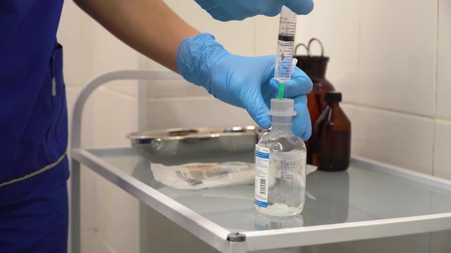 The doctor prepares a syringe with an injection and saline solution