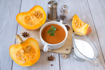 umpkin puree soup, pumpkin, spices on a wooden white background.