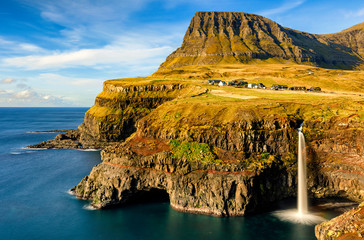 Village Gasadalur, waterfall Mulafossur and rainbow above North Atlantic ocean. Island of Vagar. Denmark. Long exposure photo © ARTem