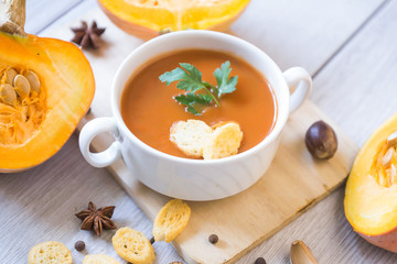 umpkin puree soup, pumpkin, spices on a wooden white background.