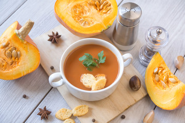 umpkin puree soup, pumpkin, spices on a wooden white background.