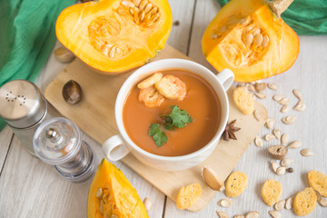 umpkin puree soup, pumpkin, spices on a wooden white background.