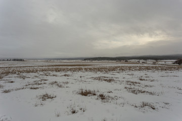 Open range covered in snow with foggy mountains on gloomy day