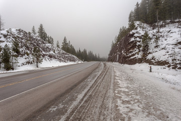 Obraz premium Fog, snow and ice surround an empty highway pass on gloomy day