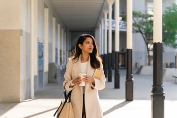 Young woman with takeaway coffee on the go in the city