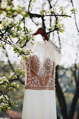 beige wedding dress hang on tree branch in garden