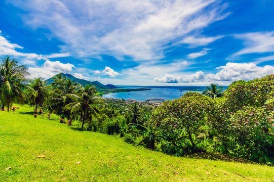 Papua New Guinea, East New Britain Province, Rabaul, Clouds over palm trees growing on green hillside of New Britain island