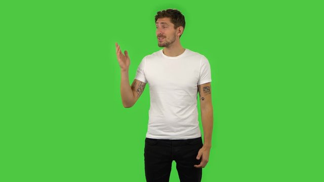 Confident guy is talking and pointing side hand for something, copy space.. Green screen