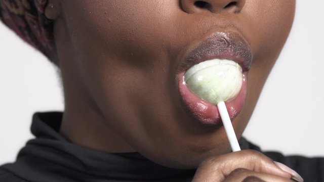Close-up of a charming African American woman with a lollipop in her mouth