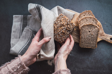 Woman's hands holding a loaf of multi seed bread.
