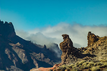 Fototapeta na wymiar Mountains and lava fields around volcano Teide, partly covered by the clouds. Bright blue sky. Teide National Park, Tenerife, Canary Islands, Spain